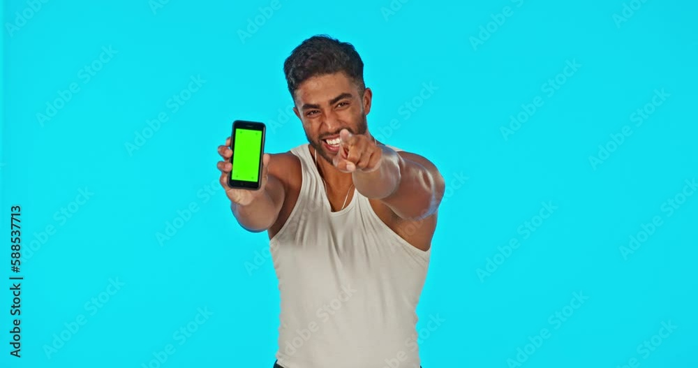 Poster face, green screen and man with phone pointing in studio isolated on a blue background. cellphone, t