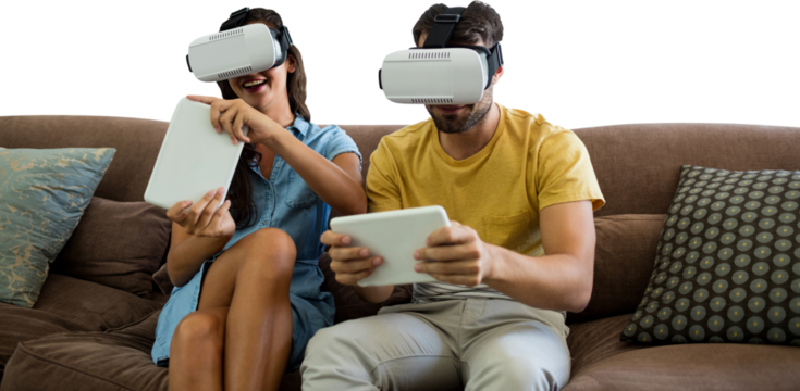 Couple wearing virtual reality glasses while using digital tablets on sofa