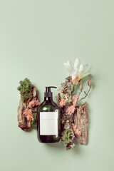 Handwash lotion on grey concrete podium and pale green background with magnolia flower and wood, top view flat lay. Minimalistic, copy space