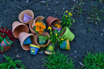 colorful ceramic pots painted in spring patterns lying on the ground among flowers in the garden