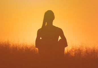 silhouette of young female sitting taking a moment to relax  in nature field feeling calm at peace 