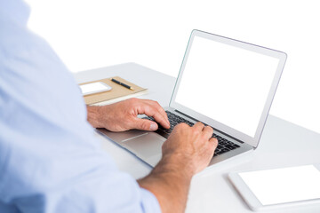 Cropped hands of male executive typing on laptop at desk