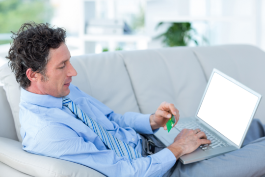 Businessman doing online shopping on couch - Powered by Adobe