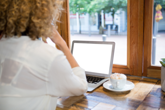 Rear view of woman using laptop at cafe - Powered by Adobe