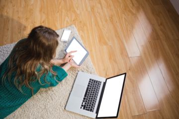 Woman lying on floor while using her tablet