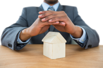 Businessman protecting house model with hands