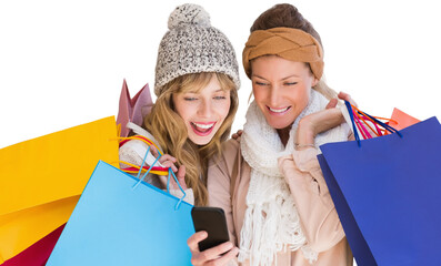 Smiling women with shopping bags looking at mobile phone 