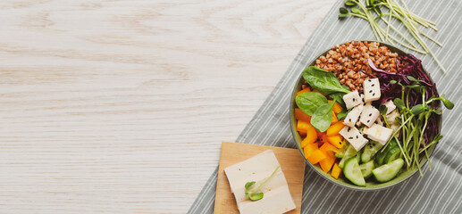 Delicious vegan bowl with bell pepper, tofu and buckwheat on wooden table, top view. Banner design with space for text