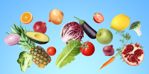 Many fresh vegetables and fruits falling on light blue background