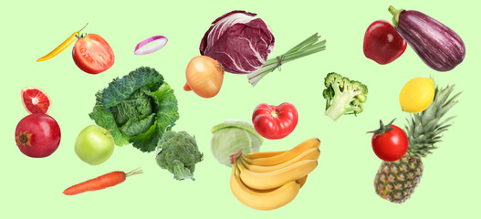 Many fresh vegetables and fruits falling on light green background