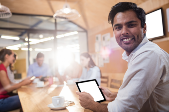Happy businessman holding digital tablet in conference room