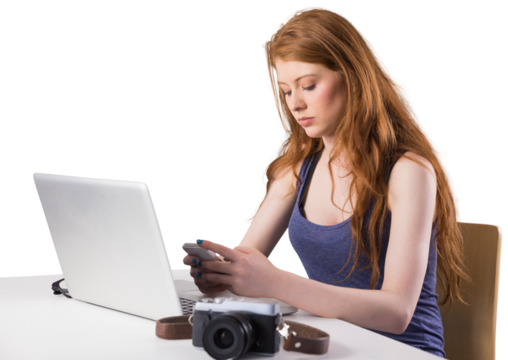 Pretty redhead working on laptop and camera - Powered by Adobe