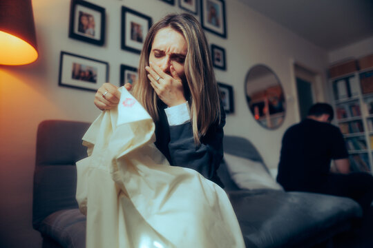 Crying Woman Discovering Proof of Adultery Deciding to Divorce her Husband. Suffering wife holding a lipstick-stained shirt of her cheating boyfriend
