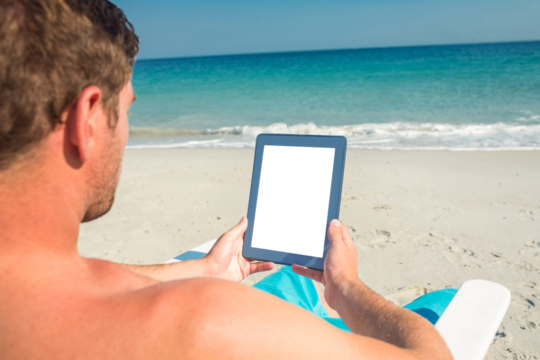 Man using digital tablet on deck chair at the beach