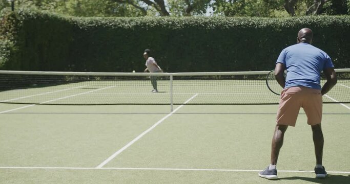 Happy Senior African American Couple Playing Tennis At Tennis Court In Slow Motion