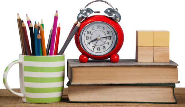 Alarm clock and books by colored pencils in mug on table