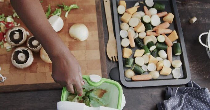 Senior african american couple throwing food waste out and cooking in ktichen in slow motion - Powered by Adobe