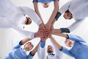 Team of medical doctors putting hands together indoors, bottom view