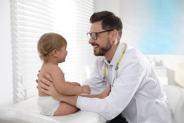 Pediatrician examining cute little baby in clinic