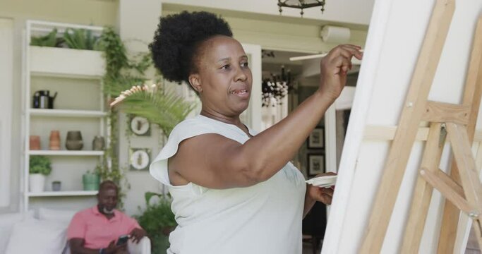 Happy senior african american woman painting in slow motion