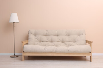 Comfortable sofa and stylish lamp near beige wall indoors