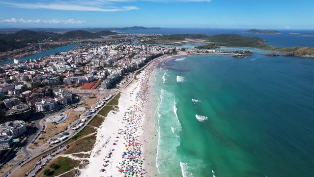 Vista do drone sobre a praia cheia de turistas e guarda-sol, mar limpo e areia branca na cidade de Cabo Frio, Rio de Janeiro, Brasil