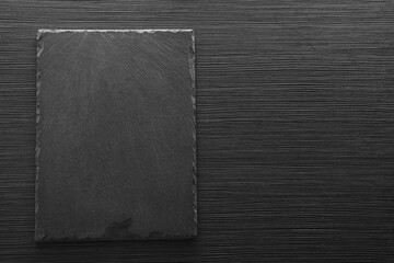 Slate board on black wooden table, top view. Space for text