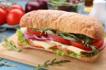 Delicious sandwich with fresh vegetables, cheese and arugula on wooden board, closeup