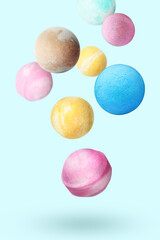 Many different bath bombs falling on pastel light blue background