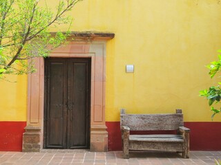 Fototapeta na wymiar traditional mexican colorful old wooden door with a bench