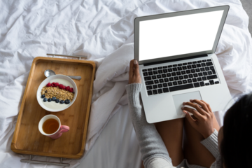 Woman with laptop while sitting by breakfast on bed