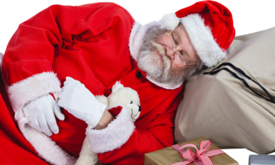 Tired Santa Claus sleeping beside Christmas presents