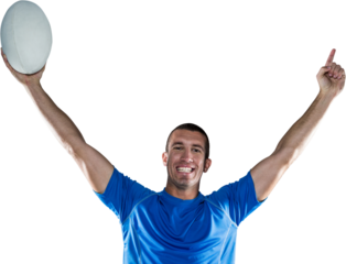 Portrait of rugby player in blue jersey holding ball with arms raised
