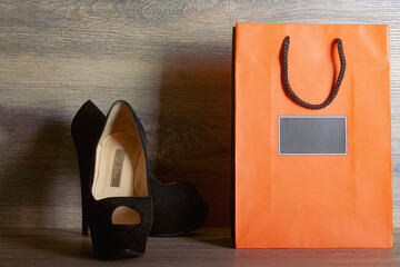 Plakat Black suede women's high heel shoes with orange paper bag