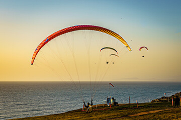 Paraglider landing with background paragliders at sunset