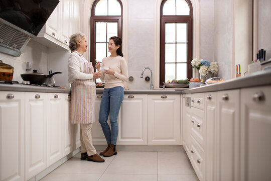 Chinese mother and daughter chattting in the kitchen