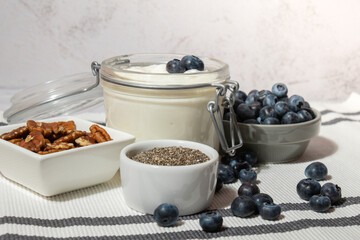 Glass jar with natural organic homemade yogurt and blueberries pecan nut chia seeds pudding. Immunity-boosting ingredients. Concept of healthy eating breakfast of Greek yogurt in glass jar and fresh