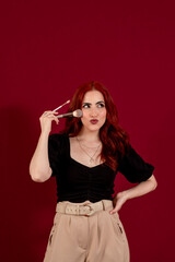 Stylish woman holding make-up brushes while posing against an isolated background.