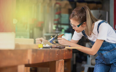 Asian carpenter woman working with carpentry tools on workbench, Carpenter Concept