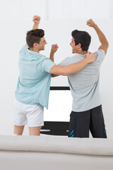 Men cheering while watching television