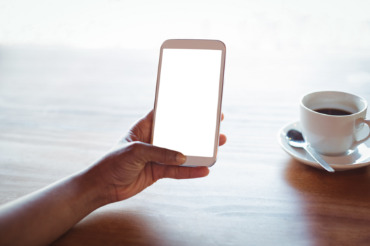 Cropped hand of woman using phone at table