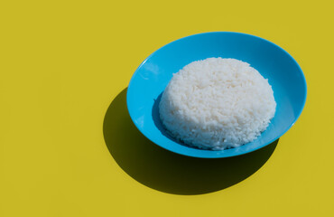 Rice in blue bowl on yellow background.