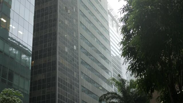 lower angle view up to the highrise skyscraper office financial building tower in the city of Singapore with stromy rain drop weather, tropical rain