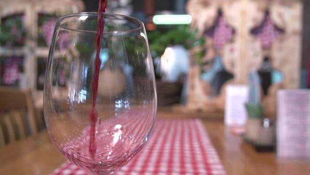 Slow motion shot of red wine being poured and filling a glass halfway