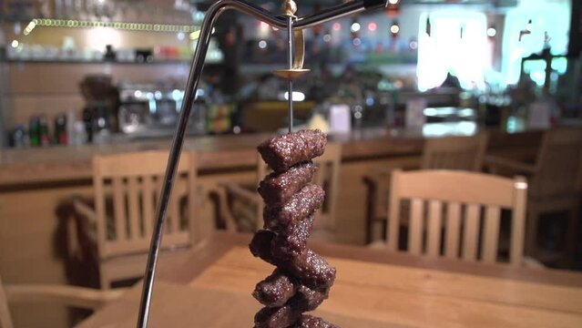 Slow motion shot of cevapcici on a skewer with cream and vegetables in a restaurant