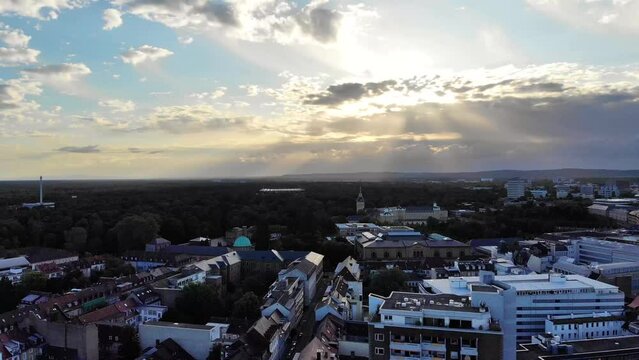 High Aerial Shot of City Building Rooftops, Streets and a Castle in front of a Beautiful Sunrise Through the Clouds, Creating Beams of Light, Karlsruhe, Germany (UHD)