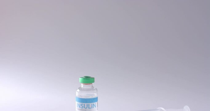 Close up of insulin vial and syringe on grey background with copy space, slow motion