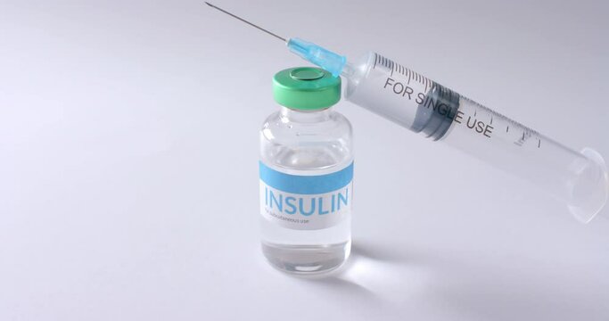 Close up of insulin vial and syringe on white background with copy space, slow motion