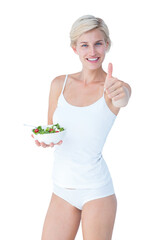 Beautiful fit woman holding a bowl of salad with thumbs up 