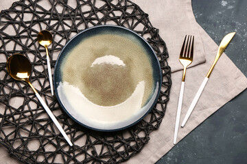 Tablecloth with plate and set of cutlery on grey grunge background